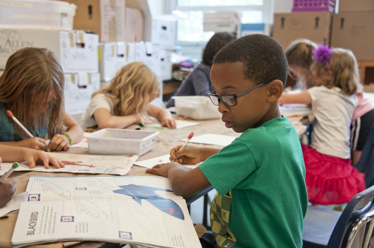 Children writing at a table in a classroom