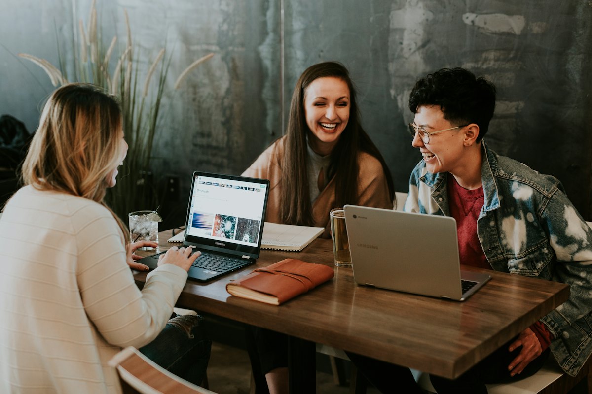 Three students laughing together over a laptop