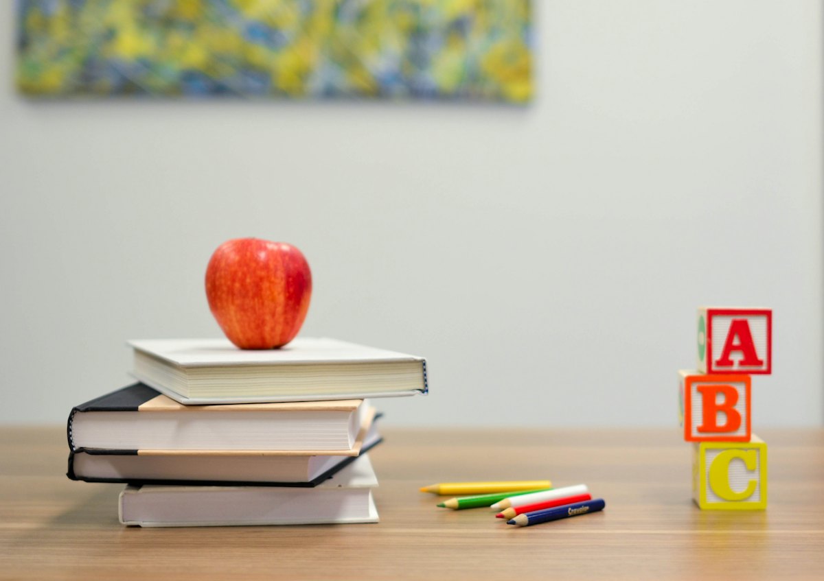 An apple on a stack of books beside alphabet blocks